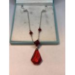 A SILVER BOXED NECKLACE WITH RED STONE PENDANT IN A PRESENTATION BOX