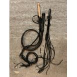 THREE LEATHER WHIPS OF VARIOUS DESIGNS TO INCLUDE A WOODEN HANDLED FLOGGER AND A BRAIDED DESIGN.