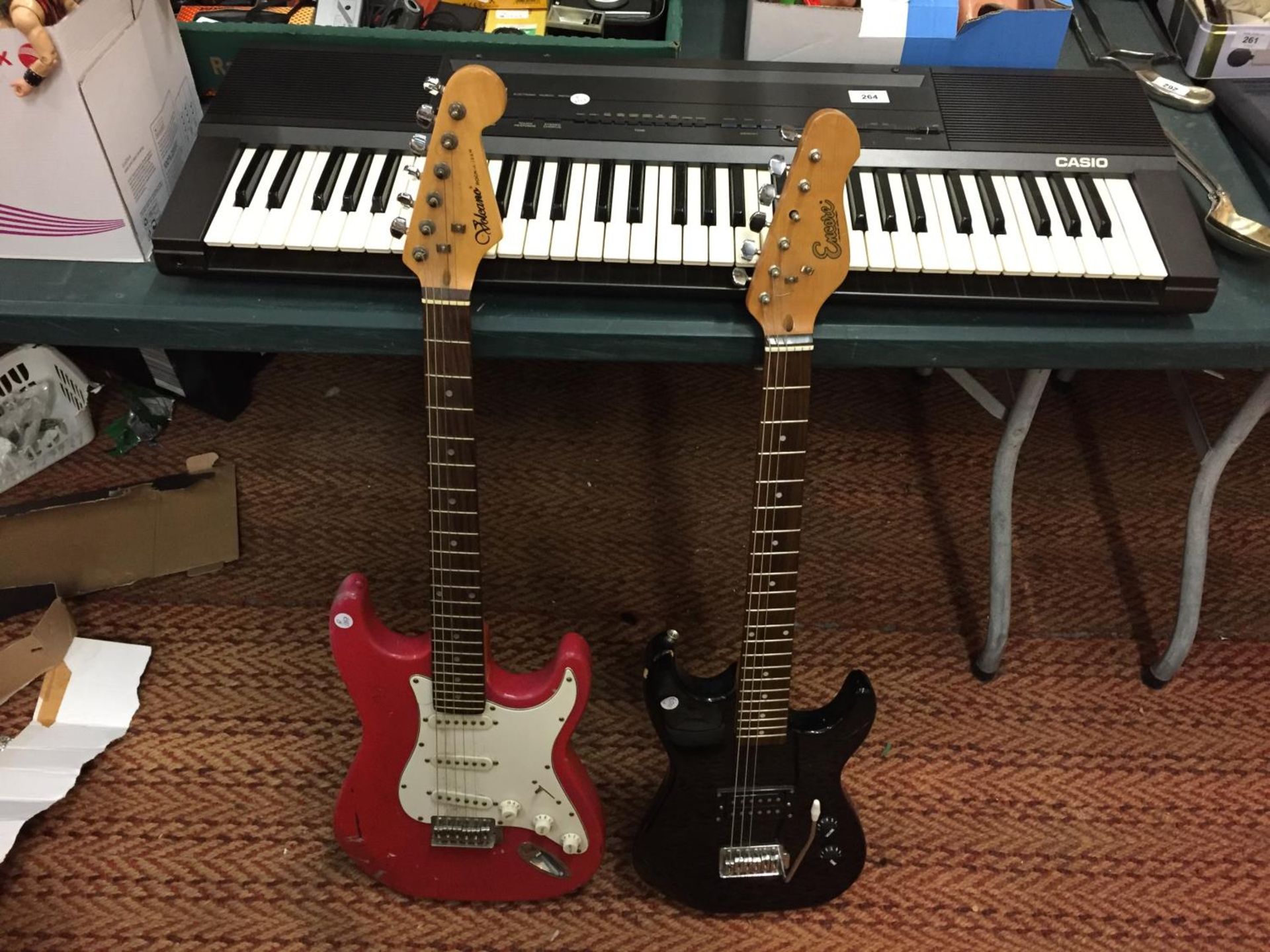 A RED VOLCANO ELECTRIC GUITAR, A BLACK ENCORE ELECTRIC GUITAR AND A CASIO KEYBOARD