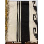 A CREAM RUG/THROW WITH A BLACK AZTEC STYLE PATTERN