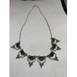 A SILVER NECKLACE WITH SEVEN RED STONES IN ORNATE SETTINGS