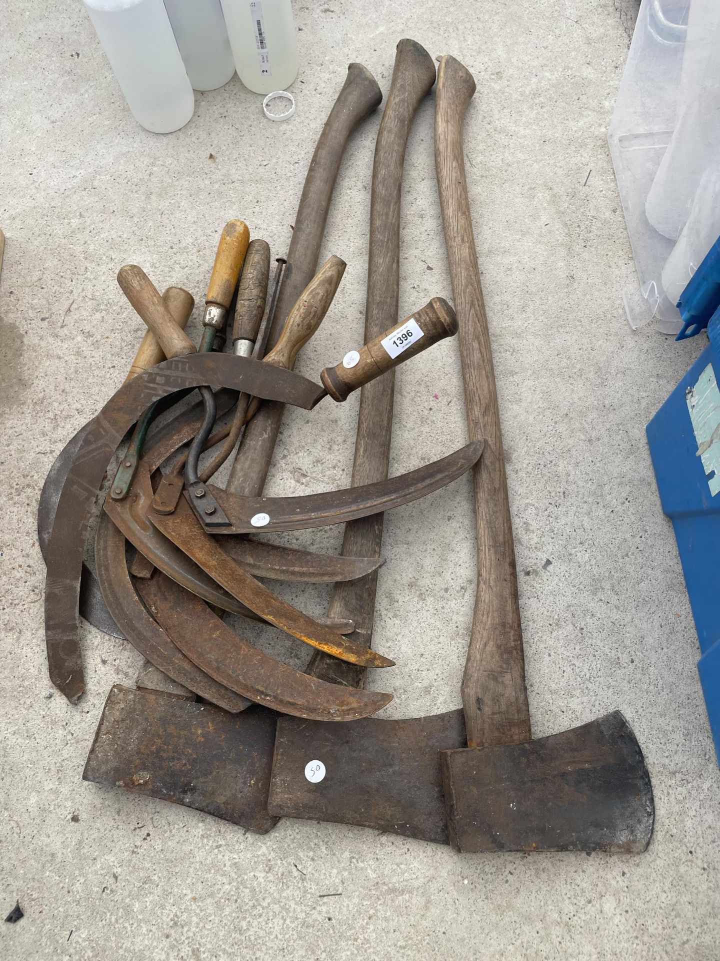 AN ASSORTMENT OF VINTAGE TOOLS TO INCLUDE SYTHES AND AXES ETC