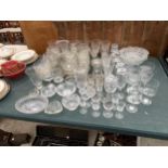 A LARGE ASSORTMENT OF GLASS WARE TO INCLUDE SHERRY GLASSES, BRANDY BALLOONS AND DESSERT BOWLS ETC