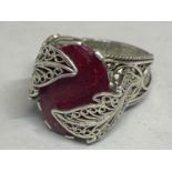 A SILVER ORNATE DESIGNER RING WITH A RED STONE EMCOMPASSED BY LEAVES DESIGN SIZE U
