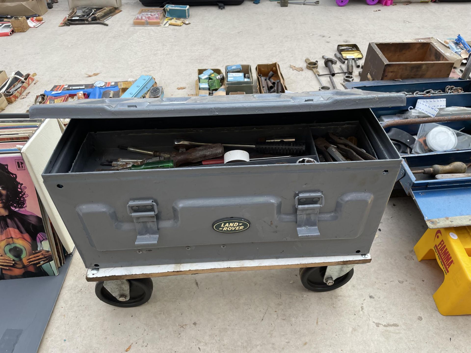 A METAL TOOLBOX AND TOOL CONTENTS WITH A LAND ROVER BADGE AND TROLLEY BASE