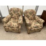 A PAIR OF EARLY 20TH CENTURY SPRUNG AND UPHOLSTERED EASY CHAIRS ON BUN FEET WITH A SPARE LOOSE COVER