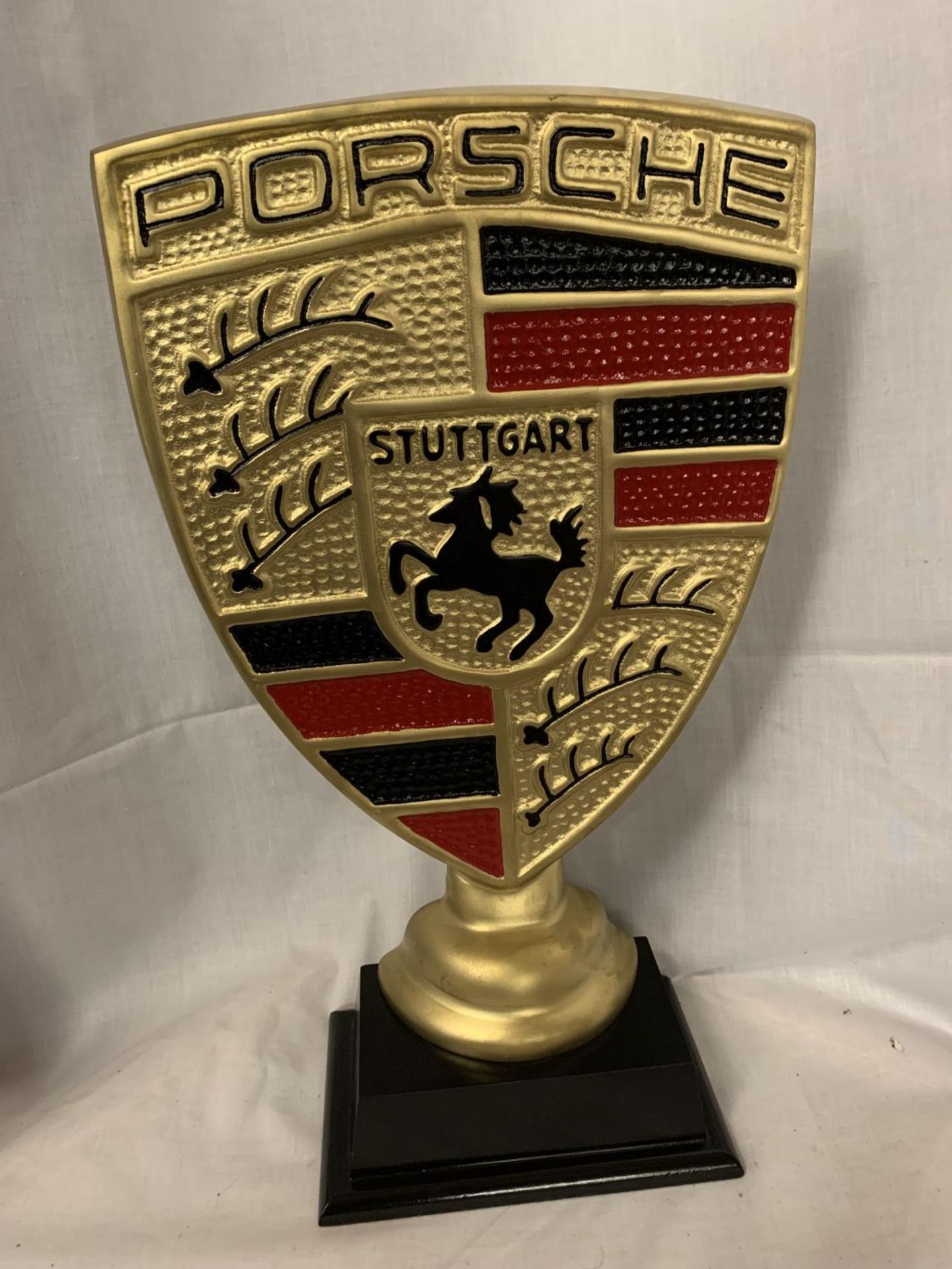 A GOLD COLOURED PORSCHE SIGN ON A WOODEN BASE 51CM TALL