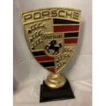 A GOLD COLOURED PORSCHE SIGN ON A WOODEN BASE 51CM TALL