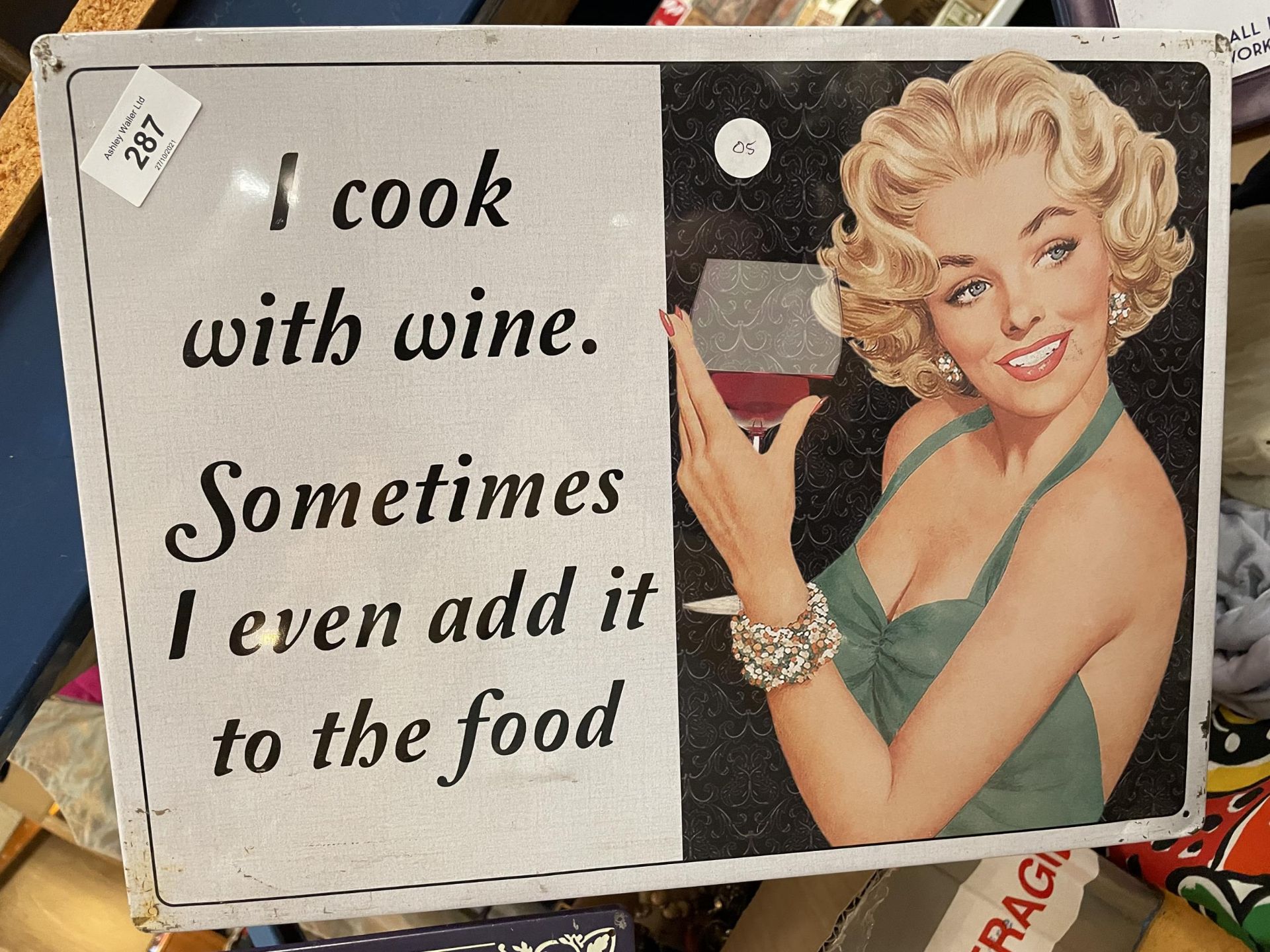 A TIN PLATE SIGN SAYING I COOK WITH WINE. SOMETIMES I EVEN ADD IT TO THE FOOD