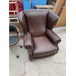 A MODERN LEATHER WINGED EASY CHAIR IN 19TH CENTURY STYLE WITH TURNED FRONT LEGS ON BRASS CASTERS