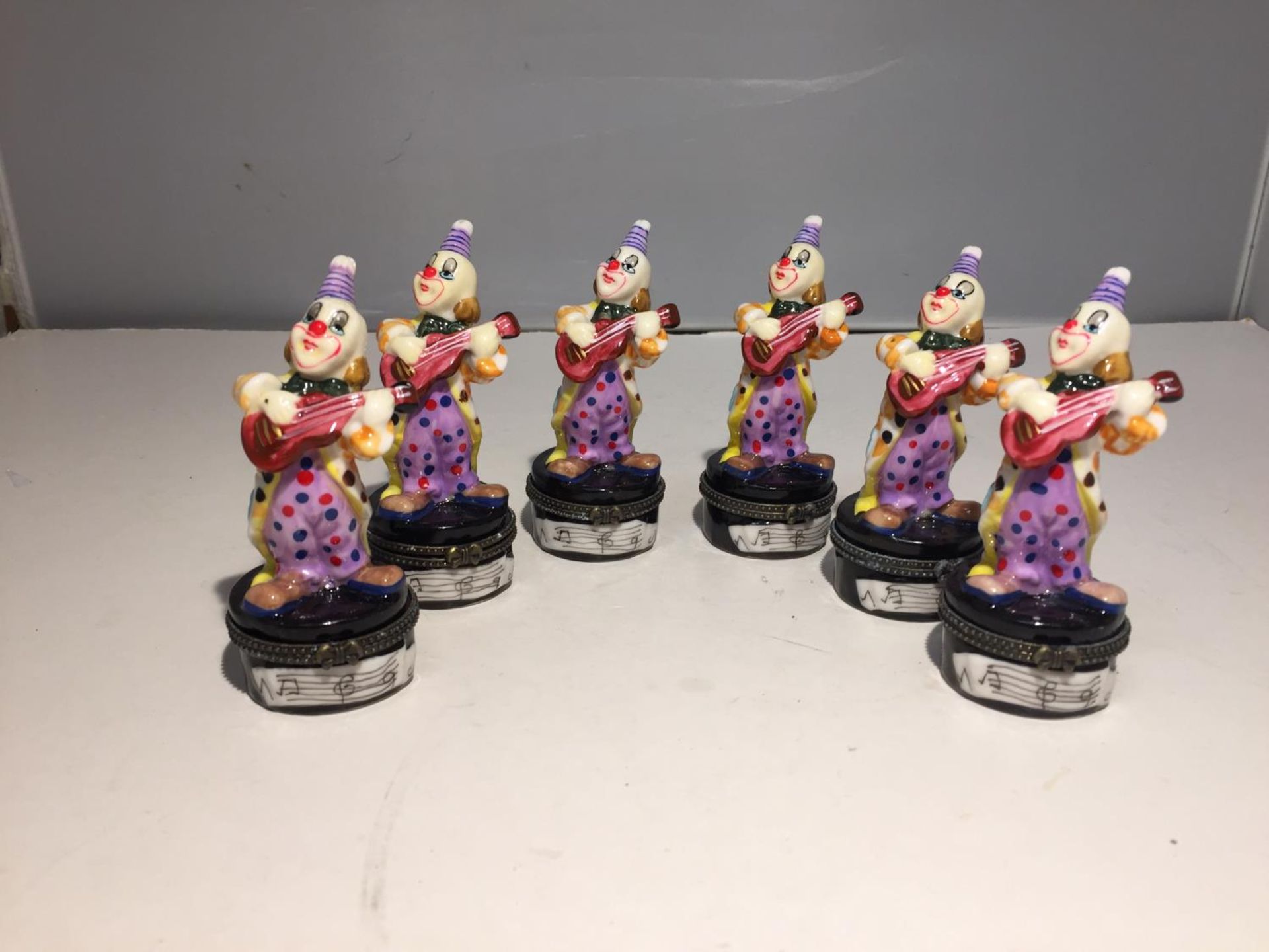 SIX TRINKET BOXES EACH WITH A GLASS CLOWN PLAYING GUITAR FIGURE