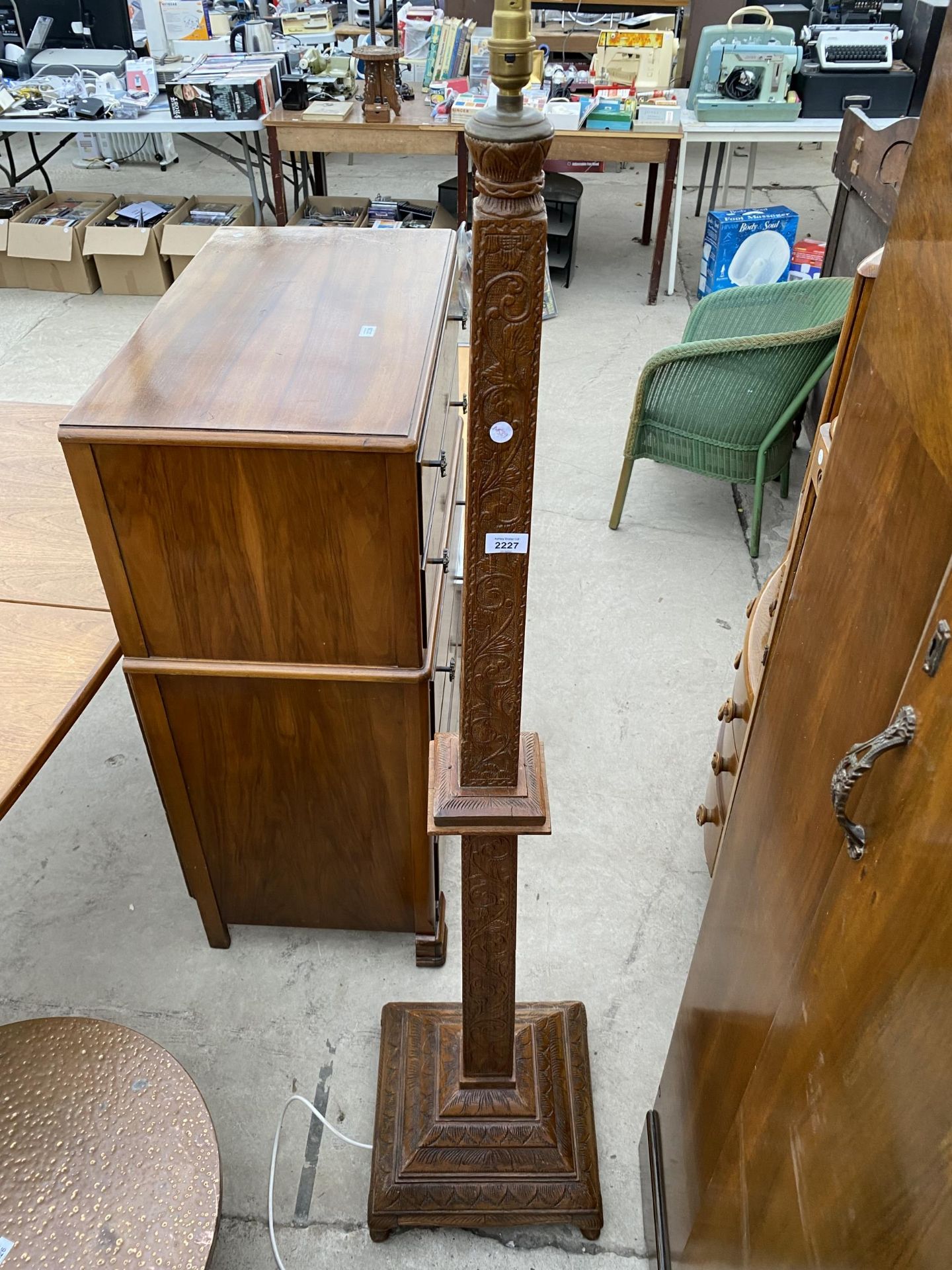 A HEAVILY CARVED TAPERING TEAK STANDARD LAMP WITH TIERED BASE