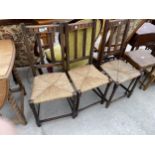 THREE EARLY 20TH CENTURY OAK CHAIRS WITH RUSH SEATS AND BARLEY TWIST SUPPORTS