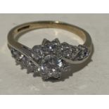 A 9 CARAT GOLD RING WITH A DECORATIVE CUBIC ZIRCONIAS IN A FLOWER DESIGN WHICH FLOWS TO THE