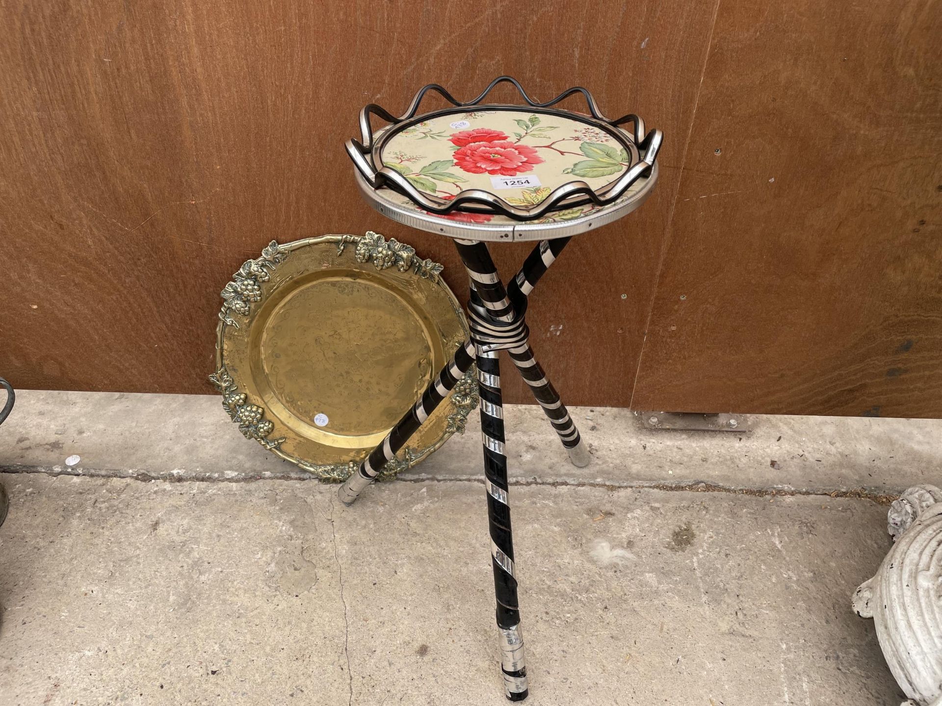 A SMALL TRIPOD BASE TABLE WITH FLORAL DECORATION AND A FURTHER BRASS PLAQUE