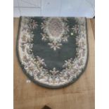 AN OVAL GHREEN PATTERNED RUG