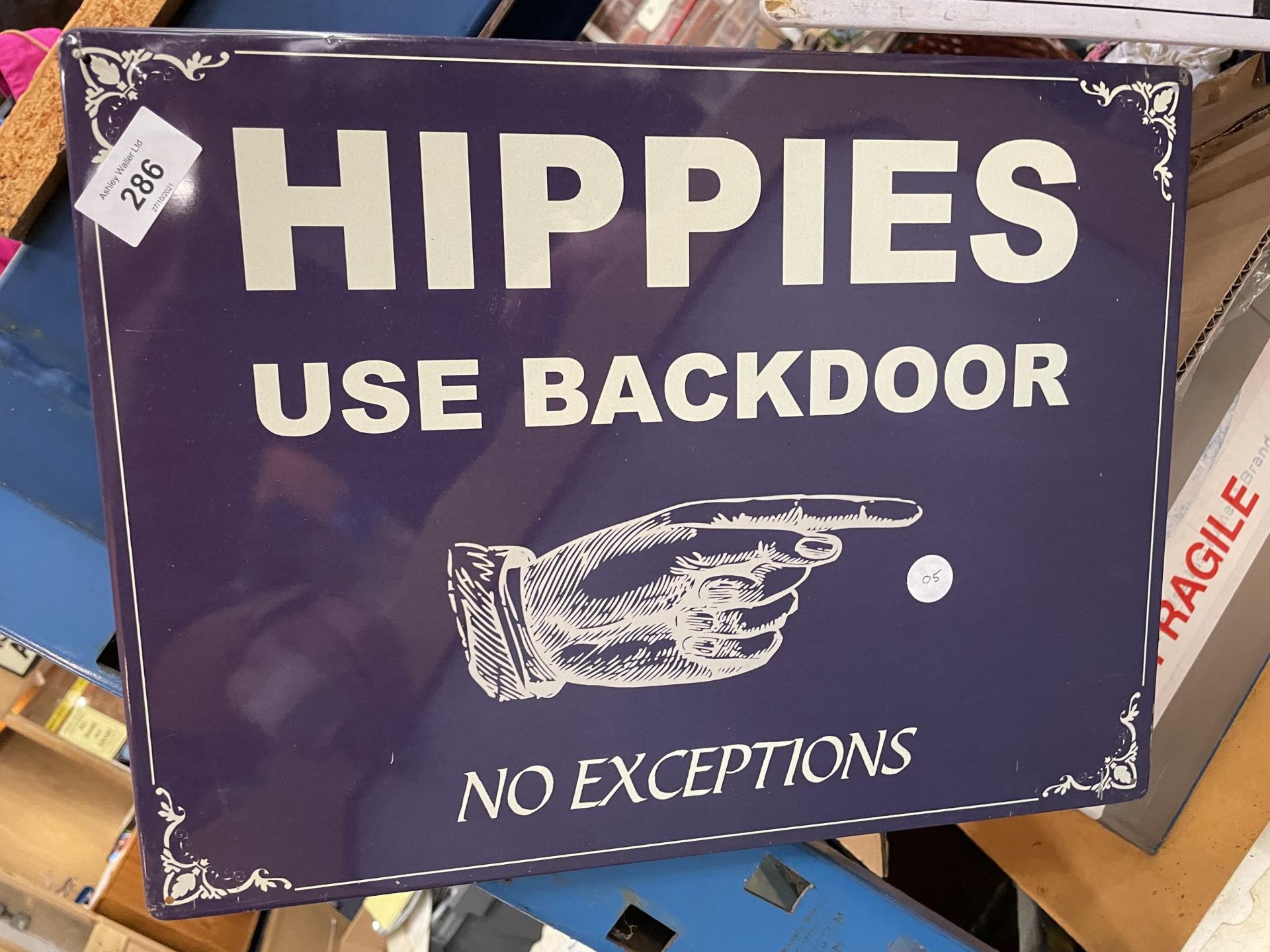 A TIN PLATE SIGN SAYING HIPPIES USE THE BACK DOOR