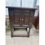 AN OAK OLD CHARM CABINET WITH TWO LINEN FOLD DOORS ON AN OPEN BASE