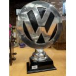 A LARGE DECORATIVE VW LOGO ON A PLINTH SIZE 50 CM