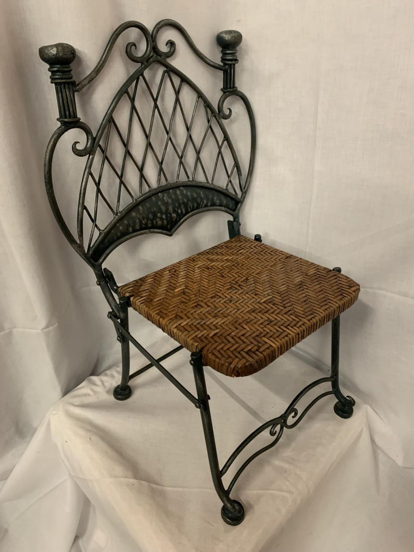 A VINTAGE VERY HEAVY WROUGHT IRON CHILDRENS CHAIR WITH A WOVEN SEAT