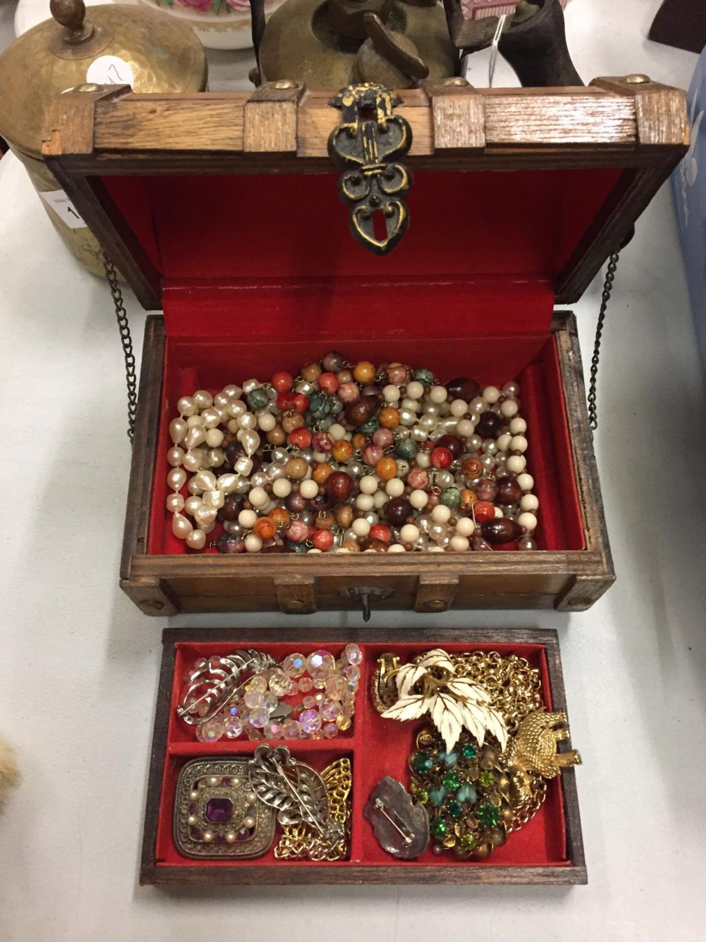 A TREEN BOX IN THE FORM OF A TREASURE CHEST CONTAINING VINTAGE COSTUME JEWELLERY TO INCLUDE