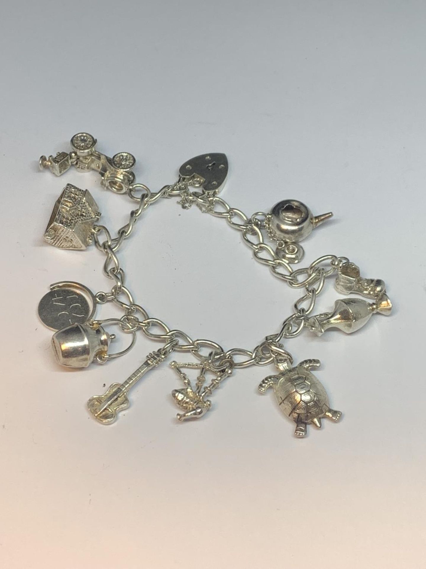 A SILVER CHARM BRACELET WITH TEN CHARMS AND A HEART LOCK