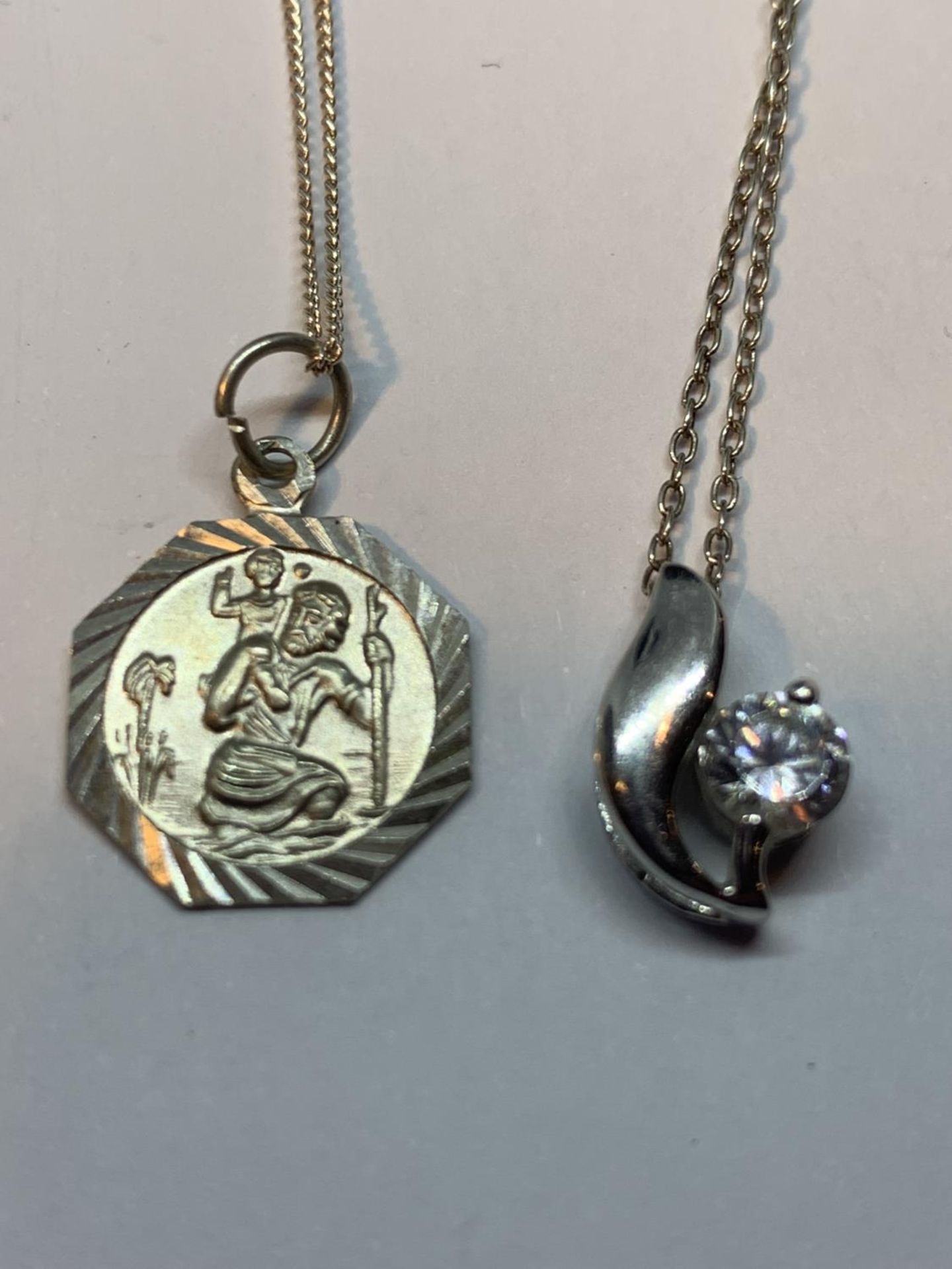 FOUR SILVER NECKLACES WITH PENDANTS TO INCLUDE A CLEARSTONE FLOWER, HEART, ST CHRISTOPHER AND AN A - Image 2 of 3