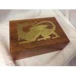 A WOODEN CIGAR BOX WITH A GOLD COLOURED DRAGON DECORATION