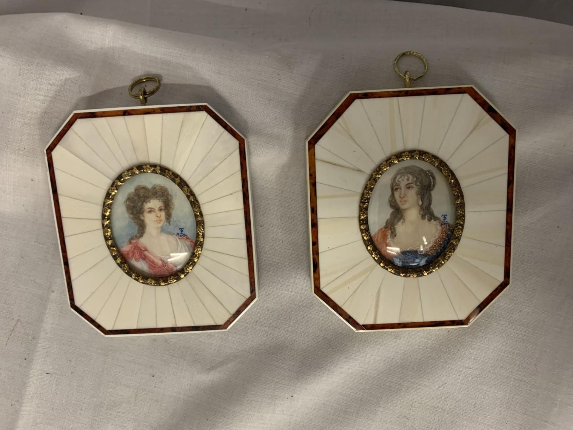A PAIR OF ART DECO STYLE BONE FRAMED MINIATURE PRINTS OF REGAL LADIES. HIGHLY DECORATIVE FRAMES WITH