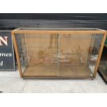 A LARGE VINTAGE SHOP DISPLAY UNIT WITH SLIDING GLASS DOORS AND INTERNAL GLASS SHELVES