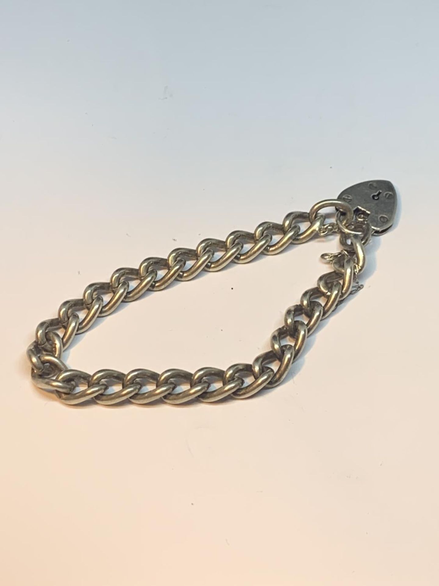 A HEAVY SILVER BRACELET WITH HEART LOCK AND SAFETY CHAIN