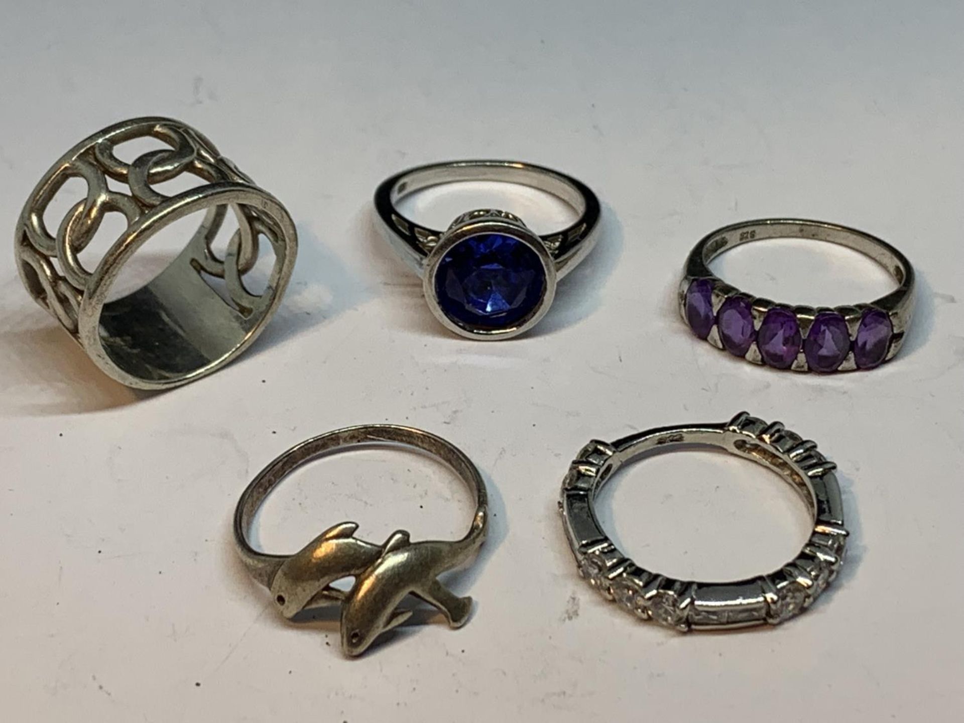 FIVE VARIOUS SILVER RINGS TO INCLUDE A BLUE STONE, PURPLESTONES, DOLPHINS ETC