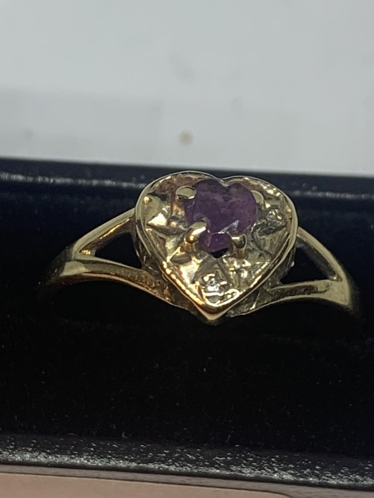 A 9 CARAT GOLD RING WITH A PURPLE STONE AND DIAMONDS IN A HEART DESIGN SIZE M WITH A PRESENTATION