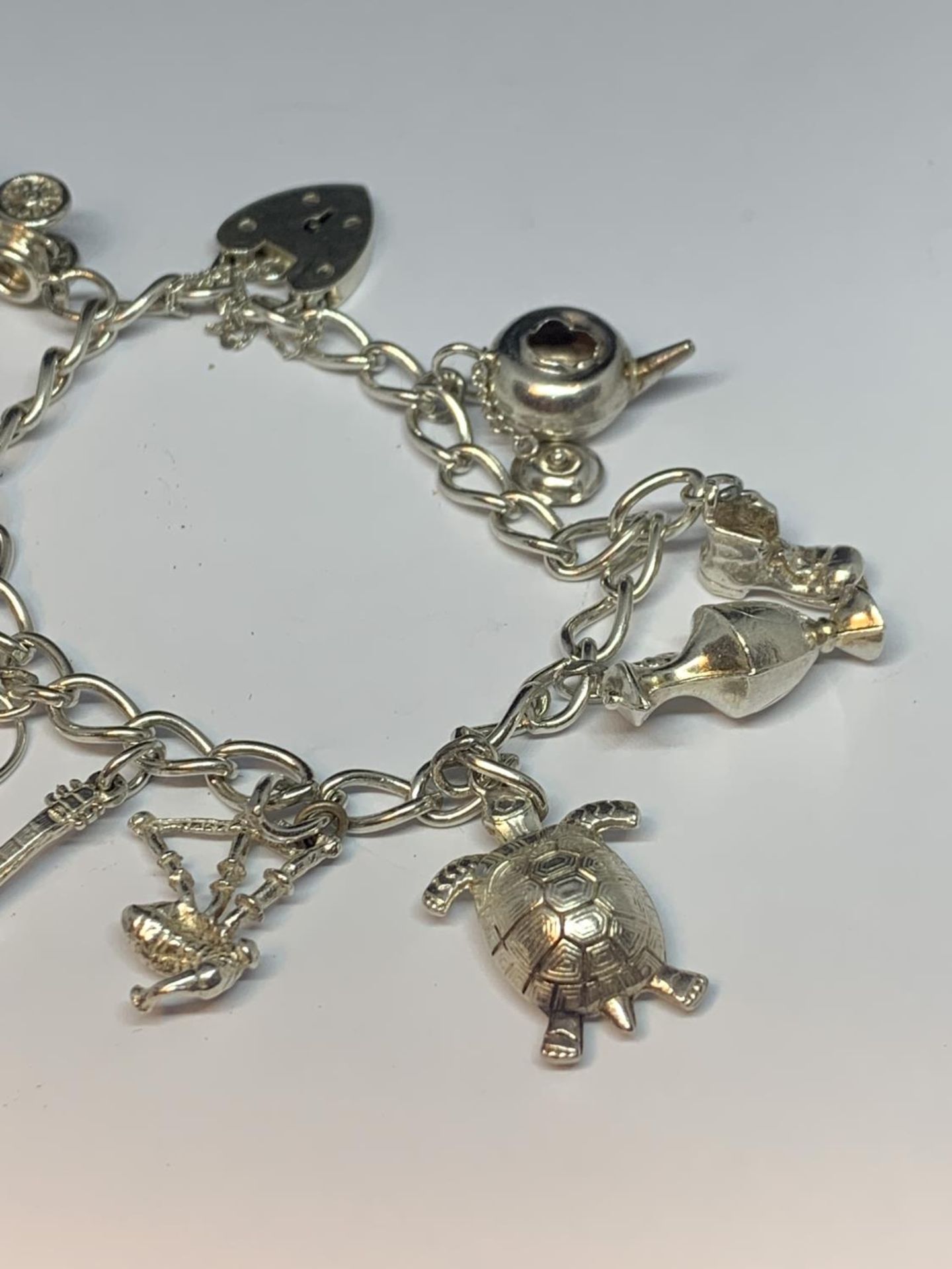 A SILVER CHARM BRACELET WITH TEN CHARMS AND A HEART LOCK - Image 3 of 3