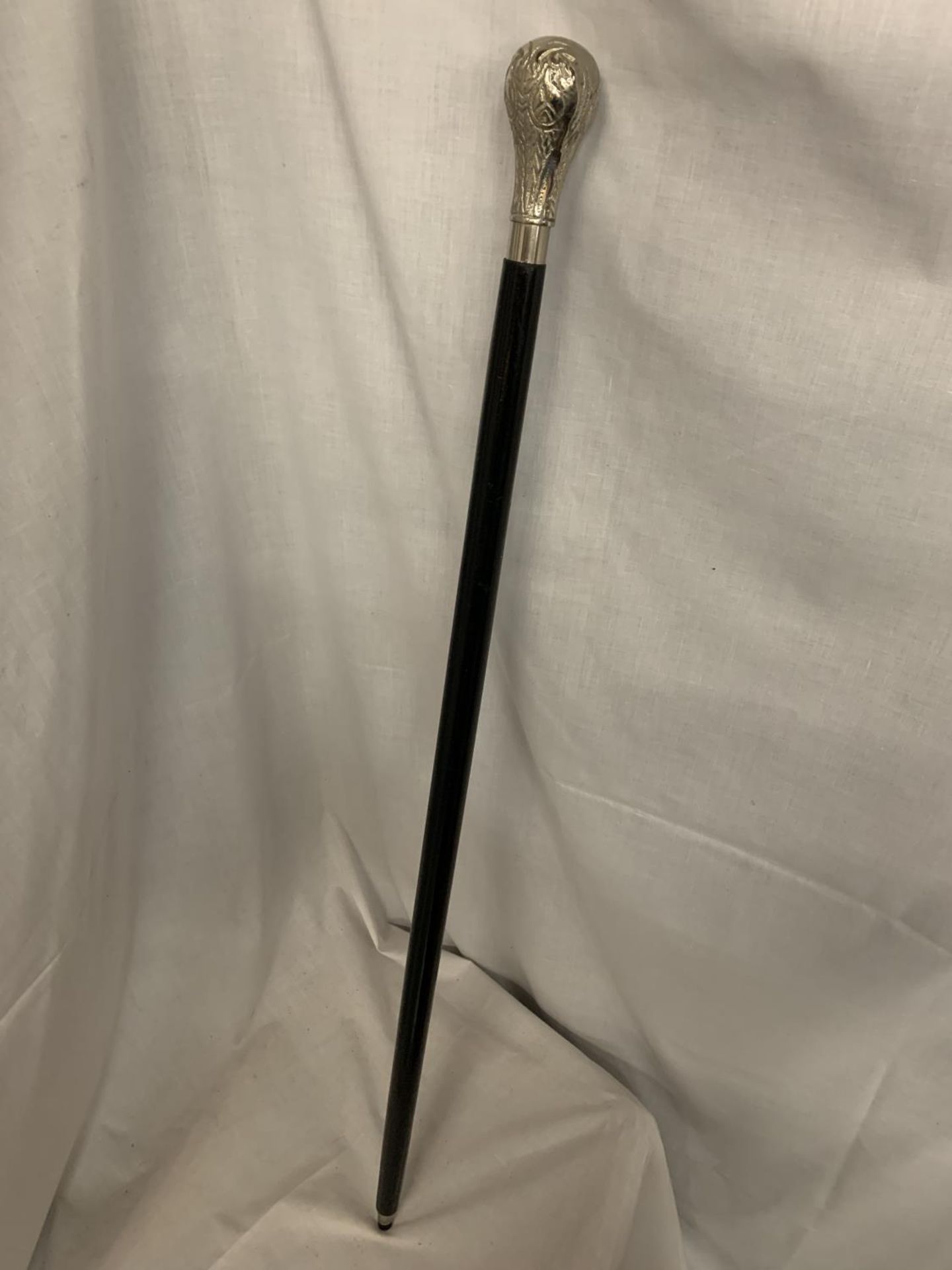 A BLACK WALKING CANE WITH WHITE METAL HANDLE