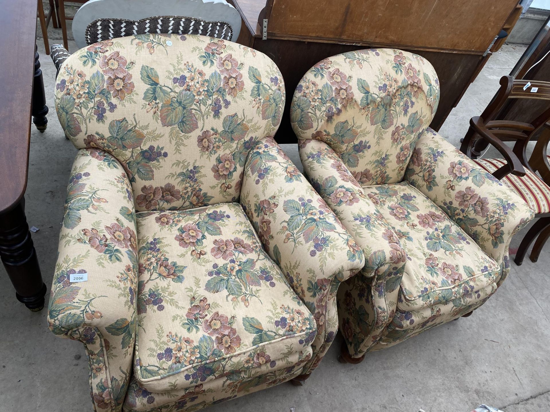 A PAIR OF EARLY 20TH CENTURY SPRUNG AND UPHOLSTERED EASY CHAIRS ON BUN FEET WITH A SPARE LOOSE COVER