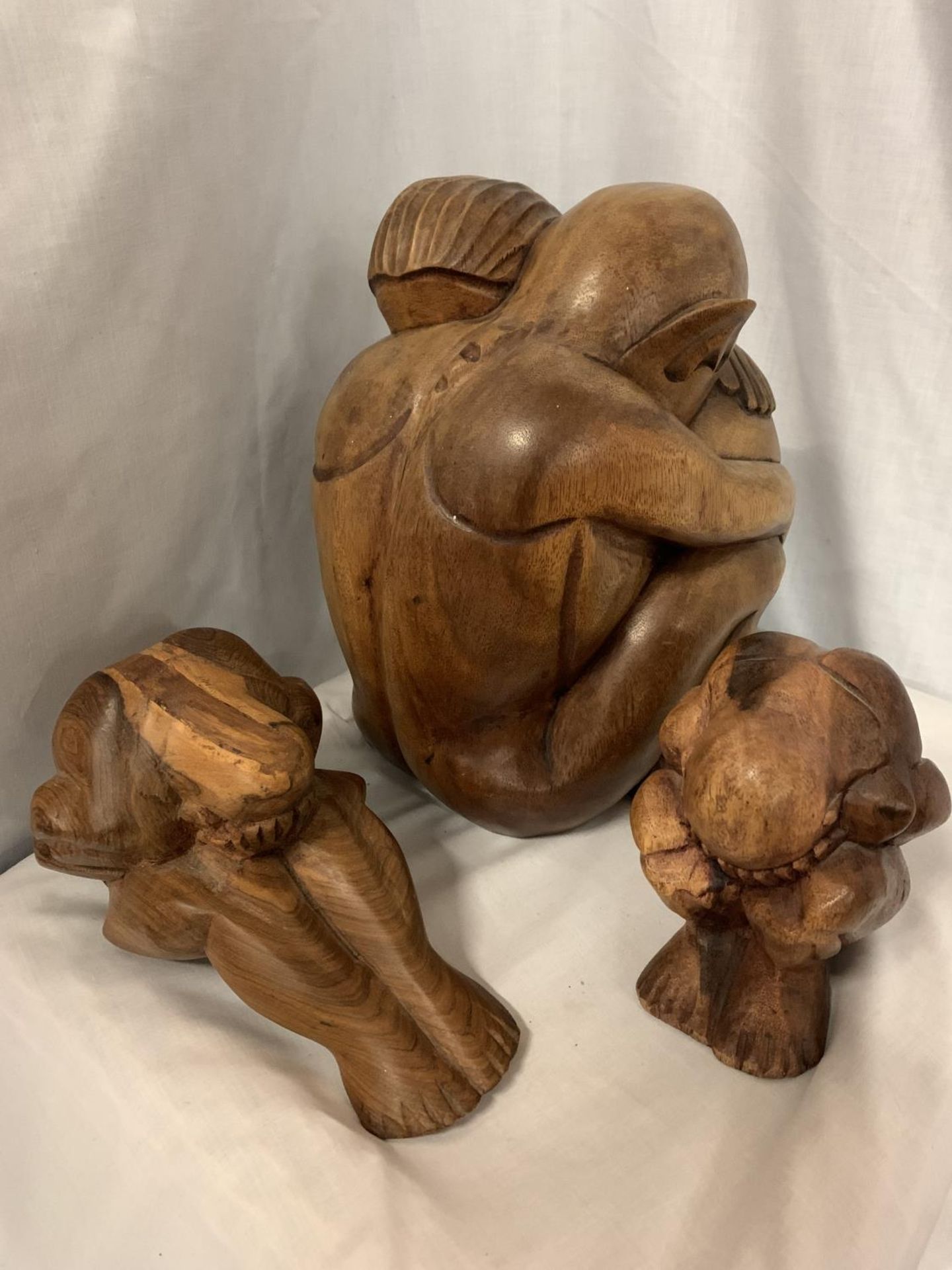 A SET OF THREE CARVED WOODEN FIGURES, ONE OF AN EMBRACING COUPLE, TWO INDIVIDUAL FIGURES