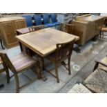 AN EARLY 20TH CENTURY OAK DINING ROOM SUITE COMPRISING DRAW-LEAF TABLE, FOUR CHAIRS AND A SIDEBOARD