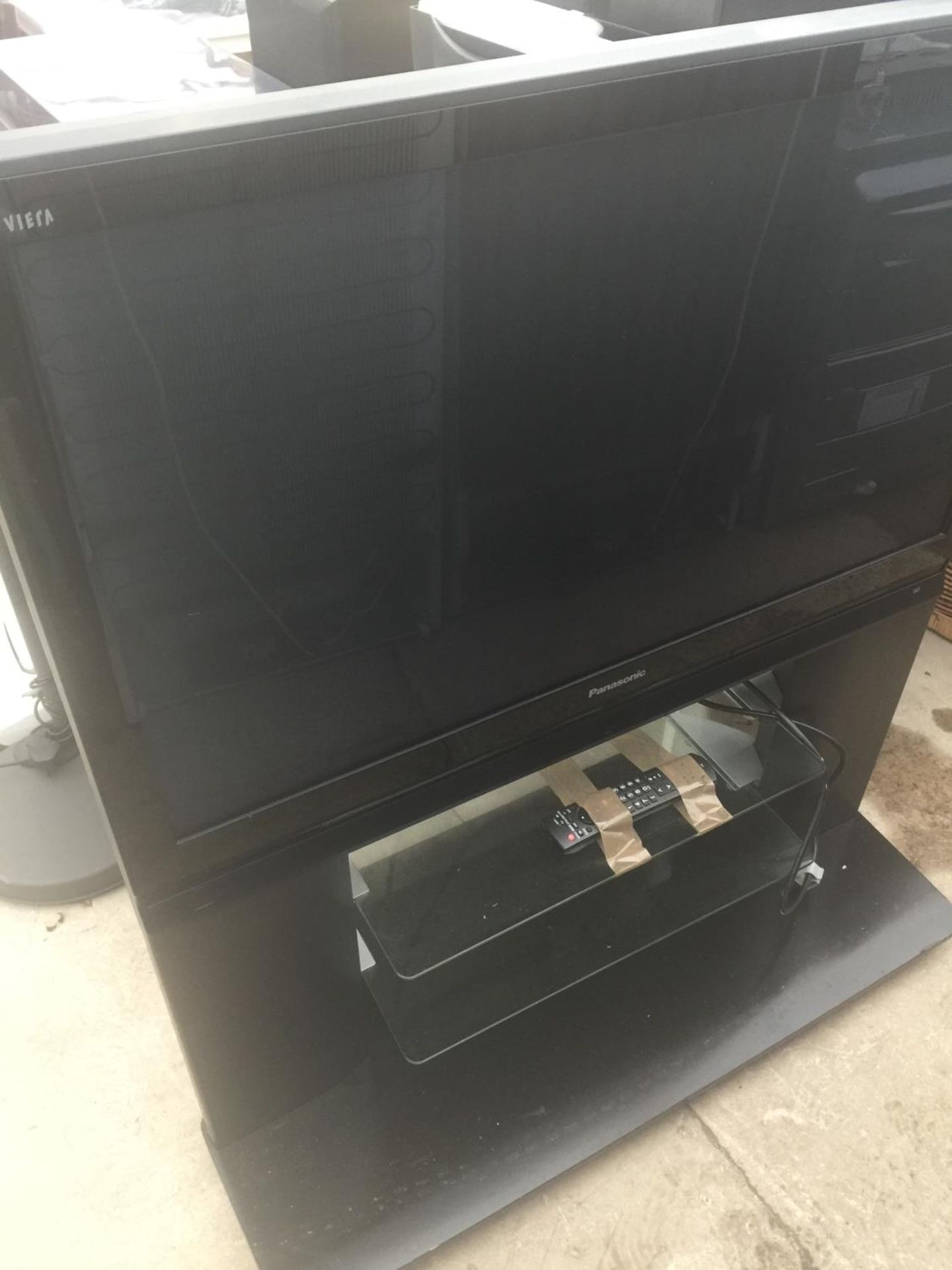 A 42" PANASONIC TELEVISION ON A STAND WITH REMOTE CONTROL