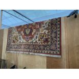 A LARGE RED PATTERNED FRINGE RUG