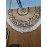 AN OVAL CREAM PATTERNED FRINGED RUG