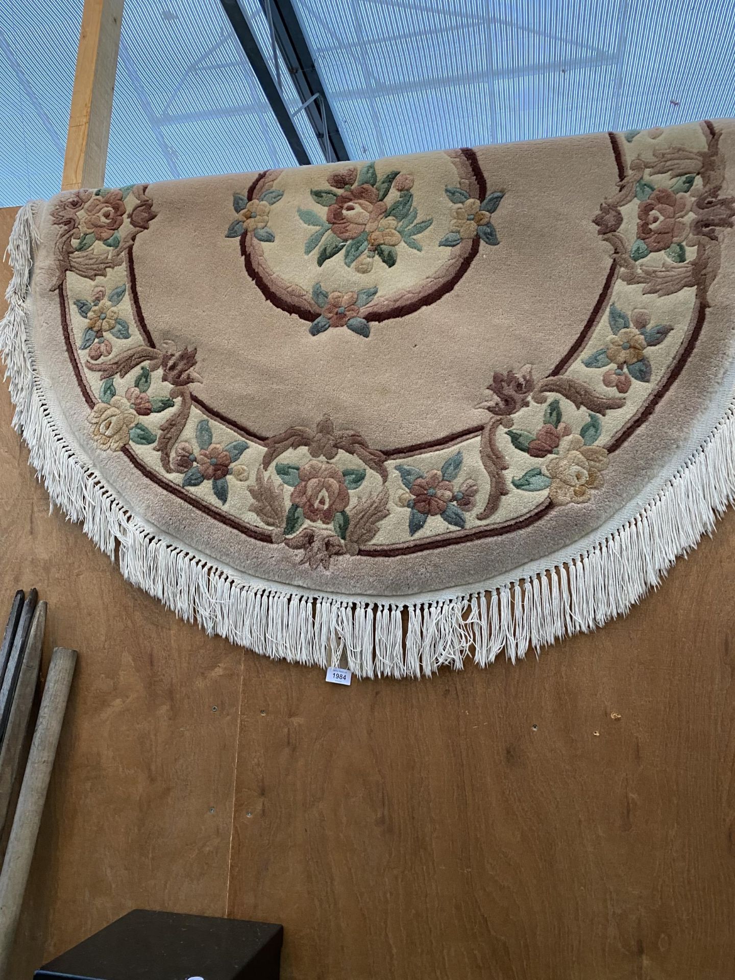 AN OVAL CREAM PATTERNED FRINGED RUG