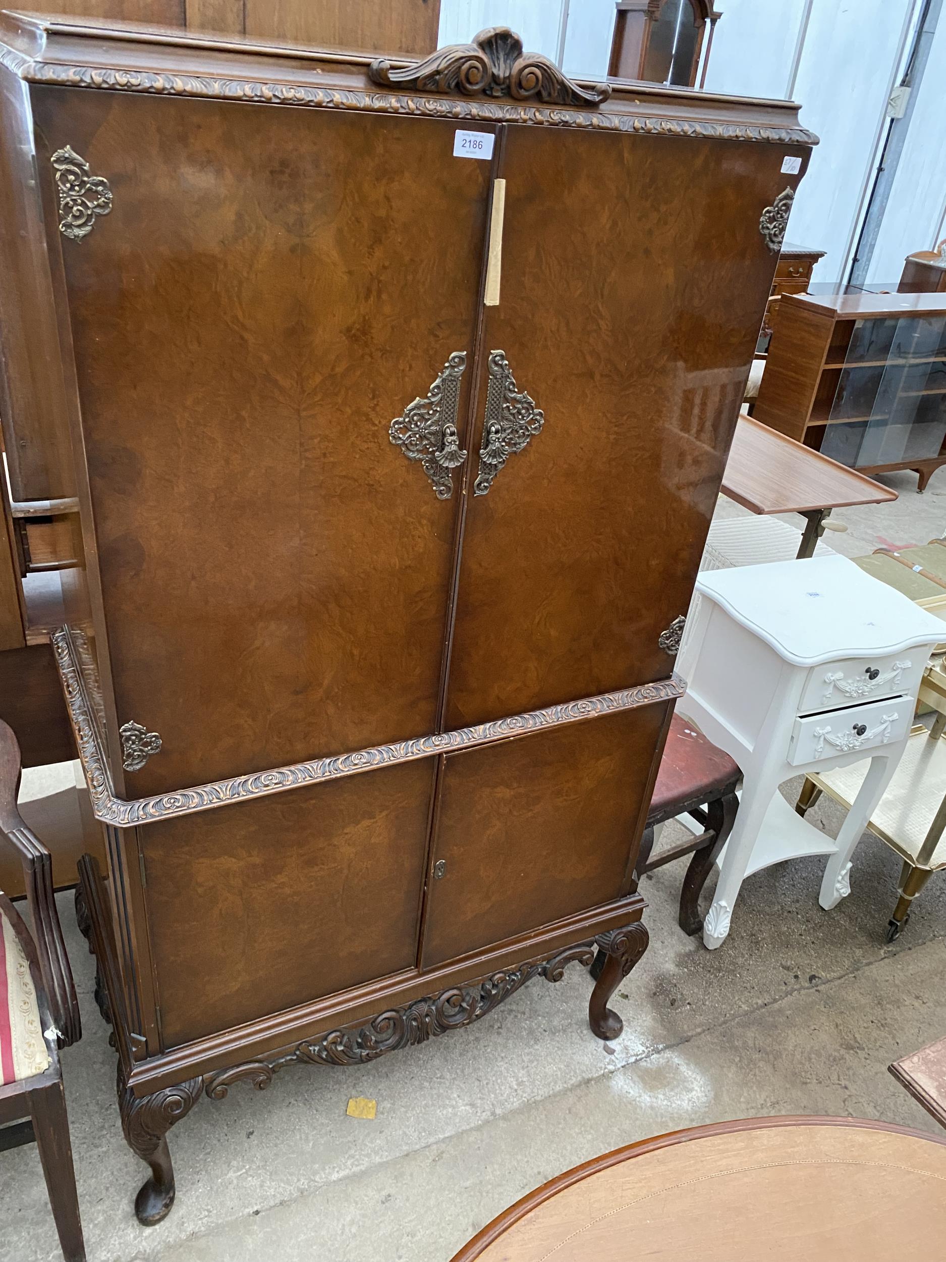 A WALNUT COCKTAIL CABINET WITH MIRRORED GLASS SLIDE ON CABRIOLE LEGS, 32" WIDE