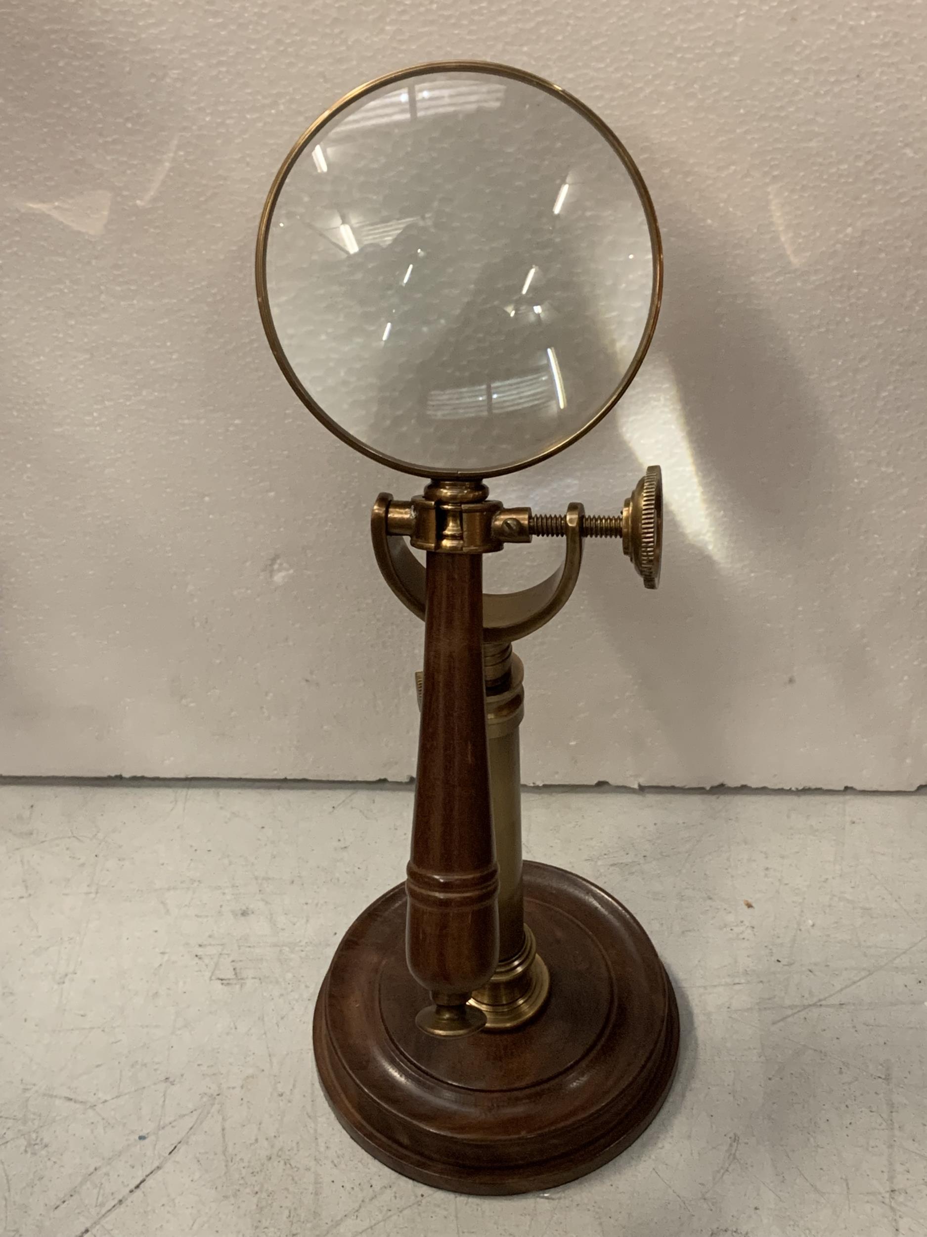 A BRASS AND WOODEN MAGNIFYING GLASS ON A STAND