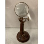 A BRASS AND WOODEN MAGNIFYING GLASS ON A STAND