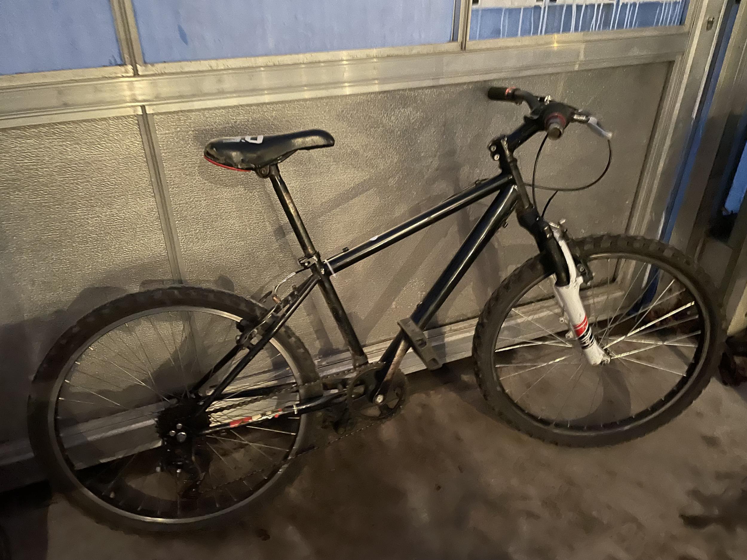 A BLAKCK MOUNTAIN BIKE WITH FRONT SUSPENSION AND 6 SPEED SHIMANO GEAR SYSTEM