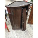 A GEORGIAN OAK BOW FRONTED CORNER CUPBOARD WITH BRASS H-HINGES (REQUIRES REPAIR TO DOOR)