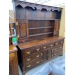 A GEORGE III OAK AND CROSSBANDED DRESSER WITH SEVEN DRAWERS AND TWO ARCHED PANEL DOORS TO THE