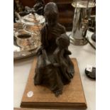 A RESIN MODEL OF A MOTHER AND CHILD ON A WOODEN BASE