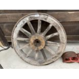 A VINTAGE WOODEN CART WHEEL WITH METAL BANDING